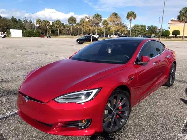 Freshly washed and waxed red sedan gleaming under palm trees