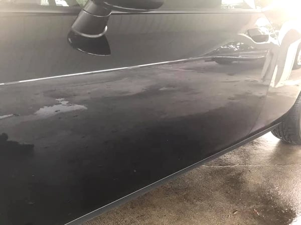Mirror-deep ceramic coating gloss on a black car panel